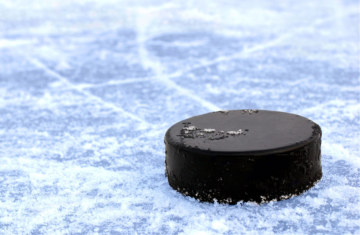 Black hockey puck on blue frosty ice